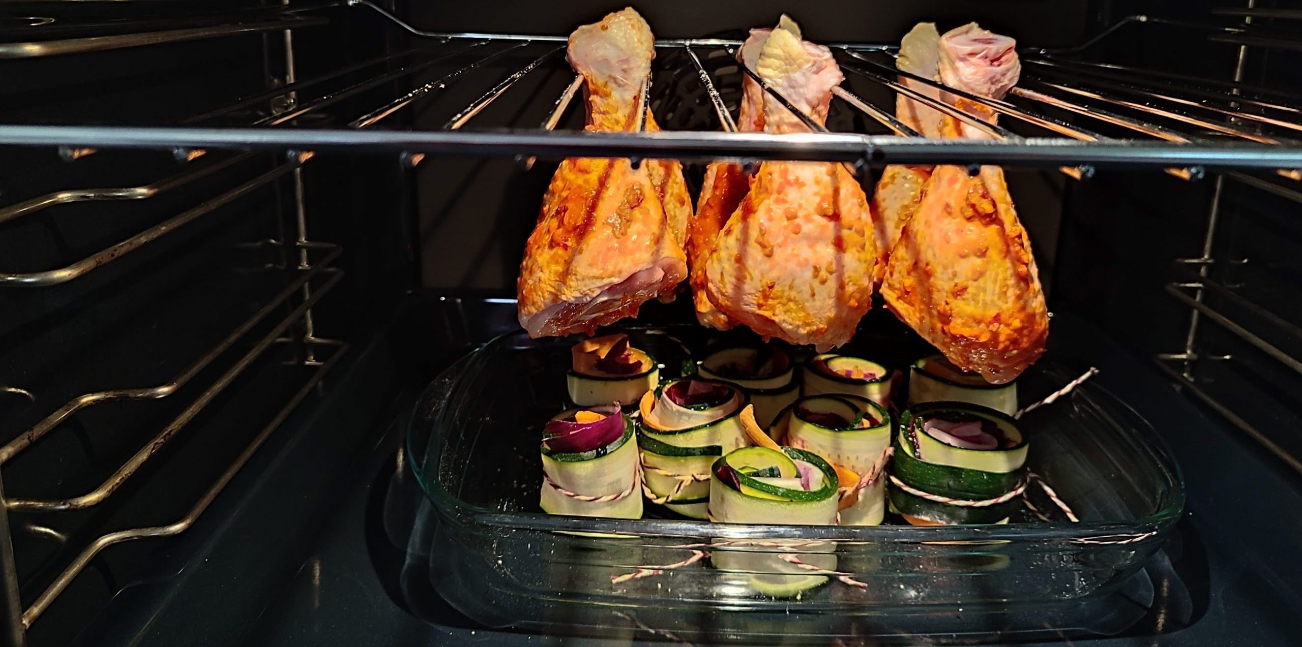 Hähnchenkeule am Galgen mit bunten Gemüserollen